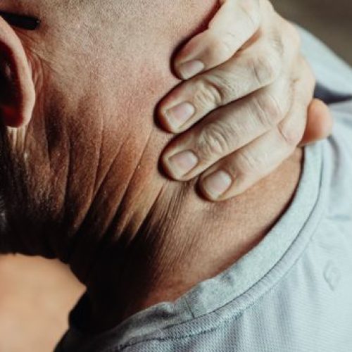 Man with neck pain holding his neck in discomfort, conveying tension or stress.